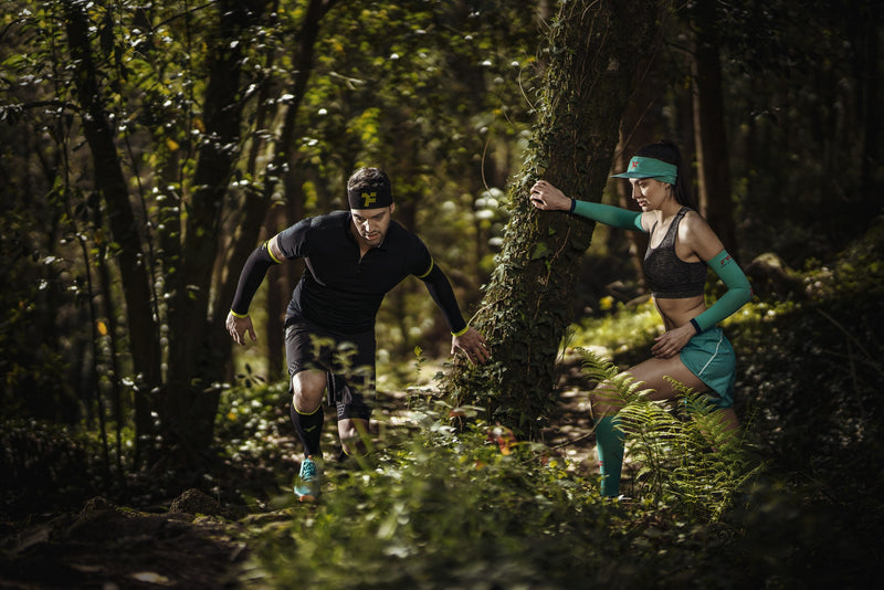 Couple trail running in forest terrain wearing Fyke sportswear.