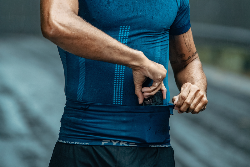 Man putting his mobile phone in a Fyke running belt