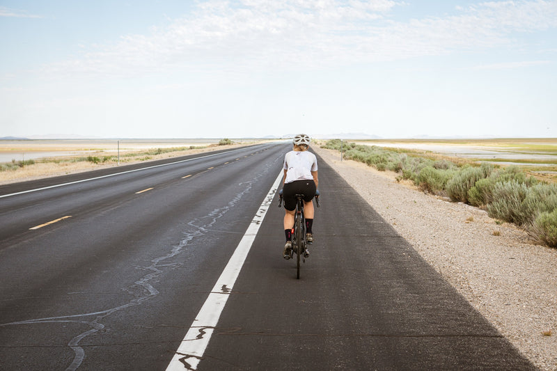 A woman cycling on a deserted road.
