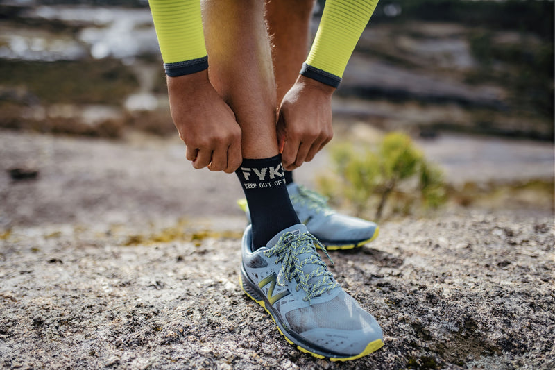 Someone pulling up Fyke's black Boost Low Sock Col2Color socks.