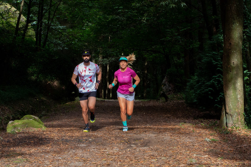 Man and woman equipped by Fyke practicing trail running in forest terrain.