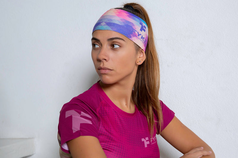 Woman with a sports headband in pink and blue tones and a pink Fyke women's sports t shirt