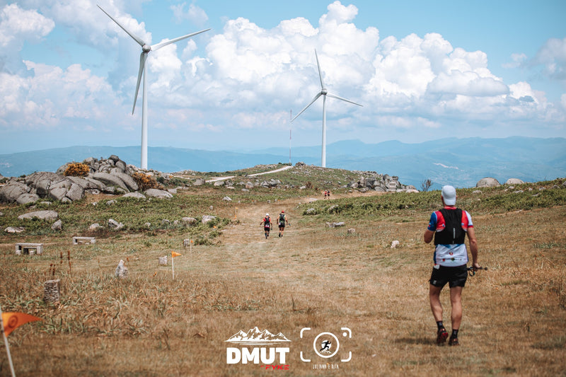 Three trail runners in a DMUT landscape with wind turbines.