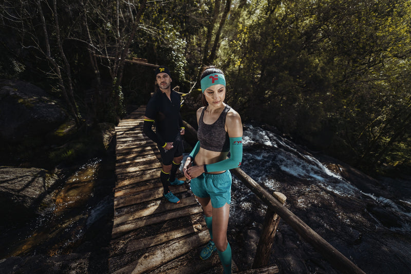 Couple with Fyke trail running equipment on a wooden bridge.