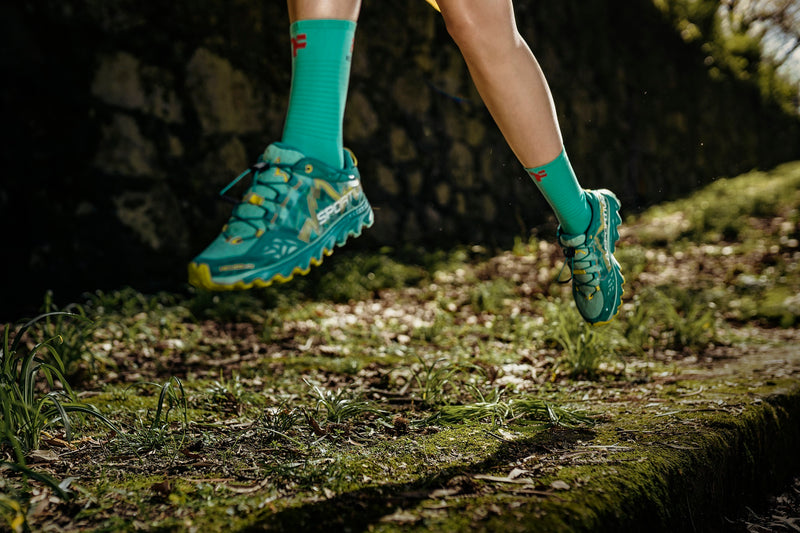 Woman running on a trail with Fyke socks.