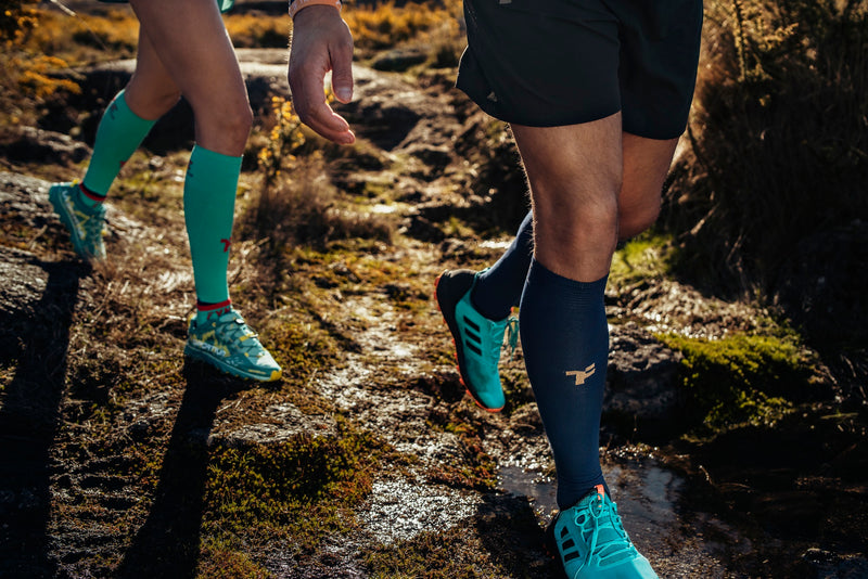 Man and woman legs running on a trail in Fyke clothes.