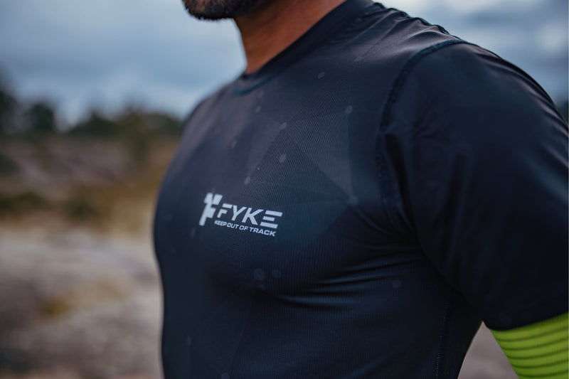 A man's chest in a black Fyke T-shirt.