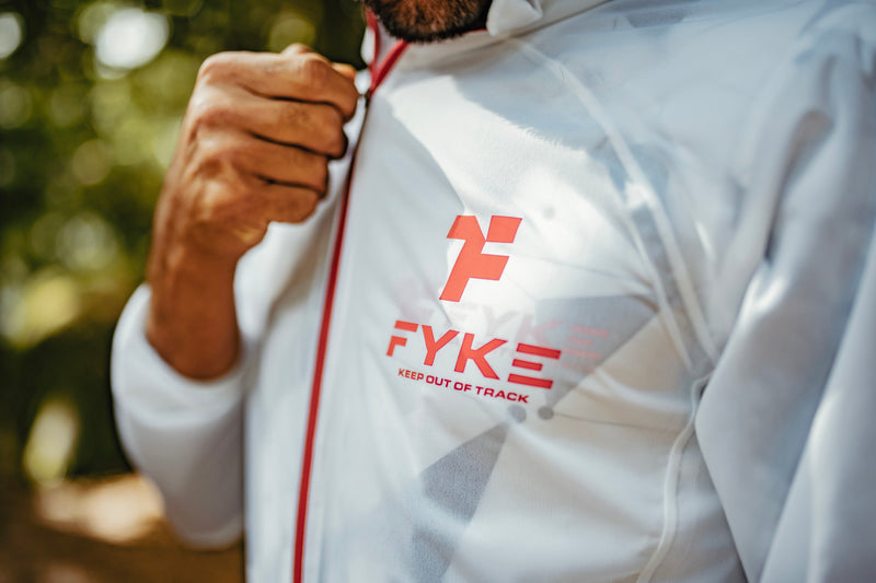 Man zipping up red and white Fyke waterproof running jacket