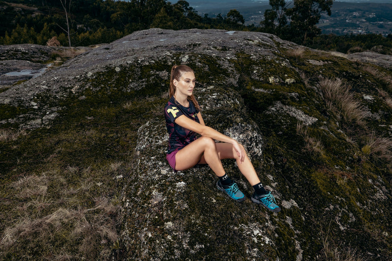 A woman in running clothes sitting on a rock.