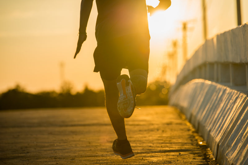 Silhouette of a man running a marathon at sunrise.