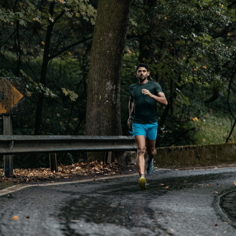 Man running on a road in the middle of a forest.