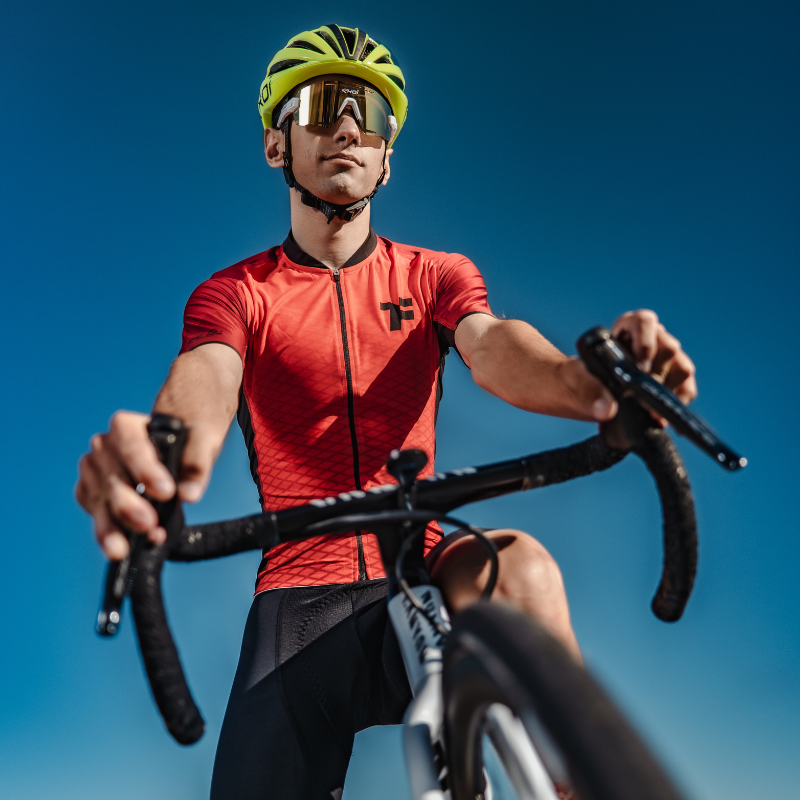 Cyclist riding a bike in a red Fyke jersey.